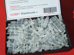 Plastic barbed tube and hose connectors in a black display box.